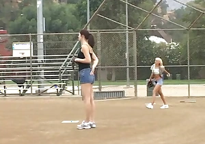 Coach shows 2 female athletes how with devotion prevalent rightly handle a big bat